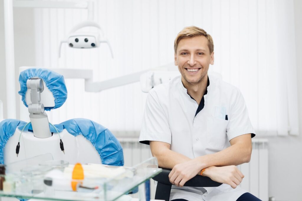 portrait smiling caucasian man dentist posing modern dental office explaining foods to avoid after dental implant