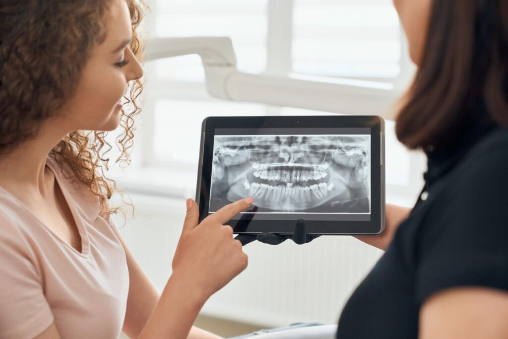 female dentist explaining * How to know if your wisdom teeth are coming in with an x ray picture teeth in a tablet