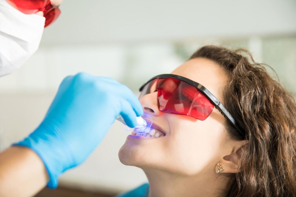 primer plano mujer joven con sus dientes blanqueados con luz ultravioleta clínica dental aprendiendo si puede blanquear sus dientes permanentemente