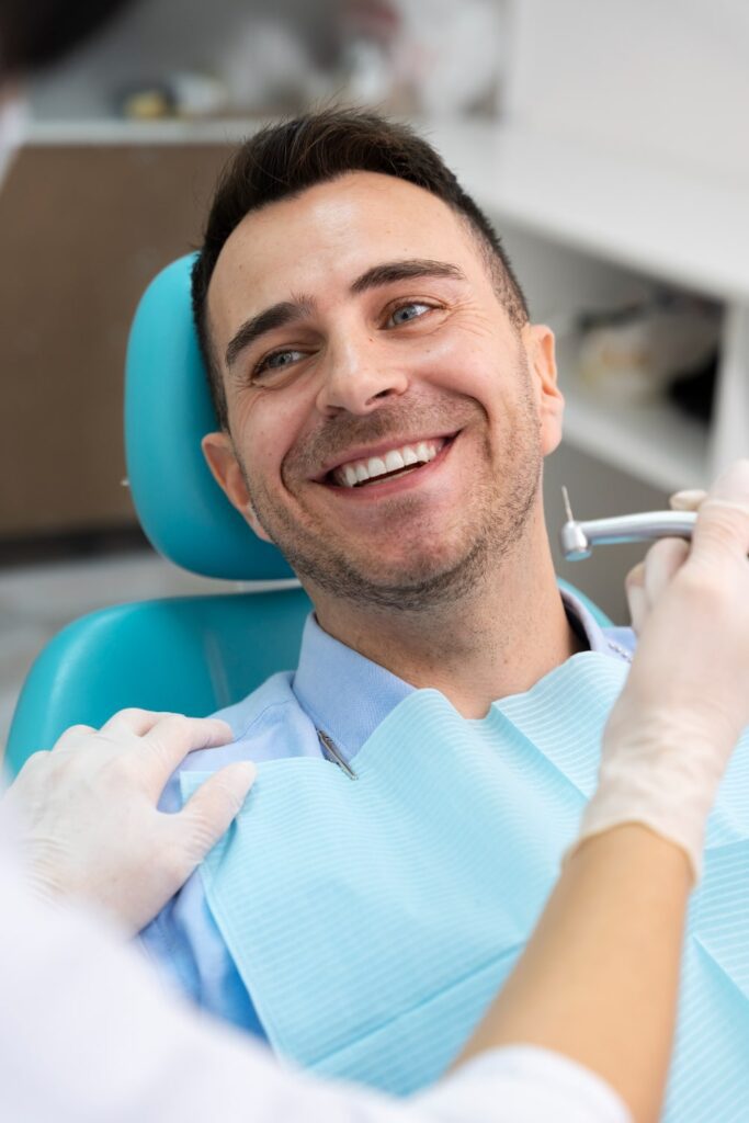 dentist with a male patient smiling with white teeth checking the results of a gum disease treatment