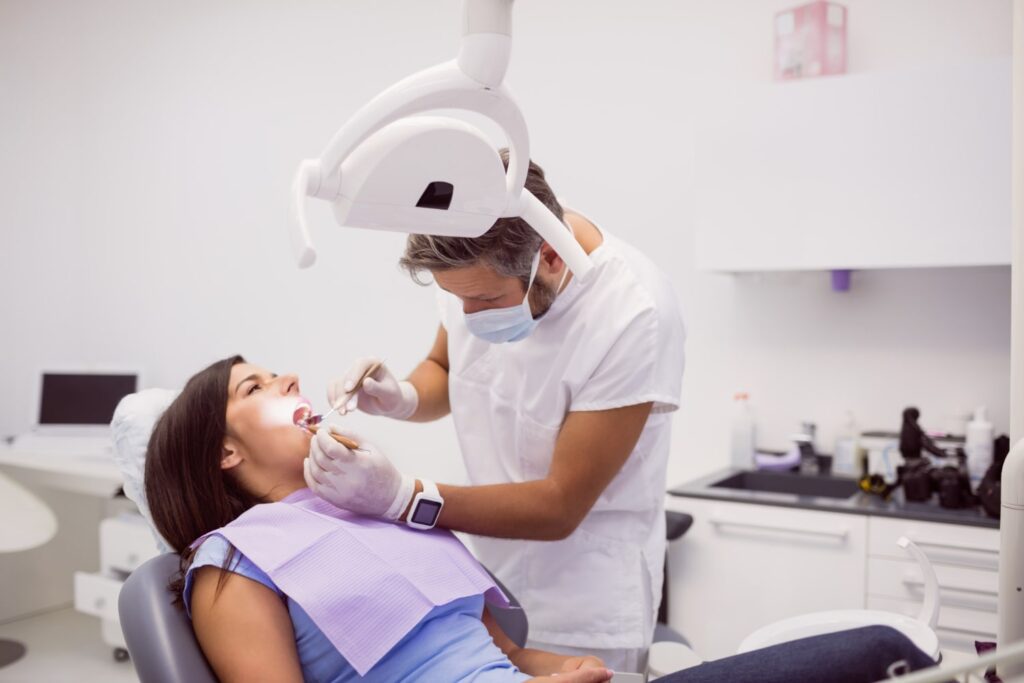 dentist examining female patient and explaining how painful is a root canal