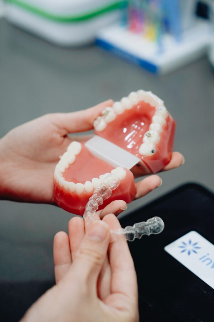 dentist showing a Invisalign retainer in an artificial denture in his clinic located in fort mill