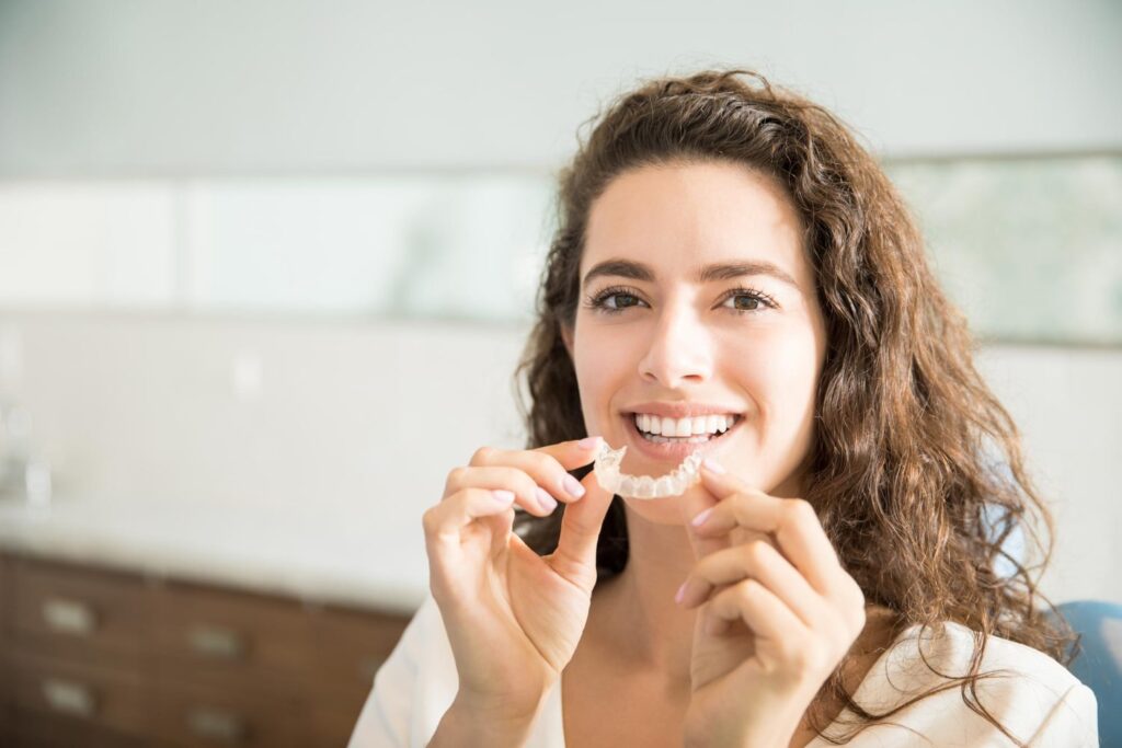 portrait beautiful patient holding orthodontic invisalign retainers in fort mill