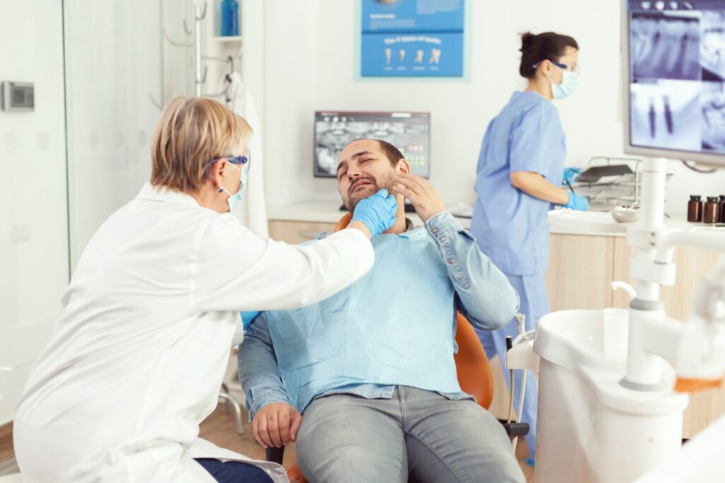 dentista revisando el dolor de dientes del paciente durante la cita explicando cómo sé si necesito un conducto radicular