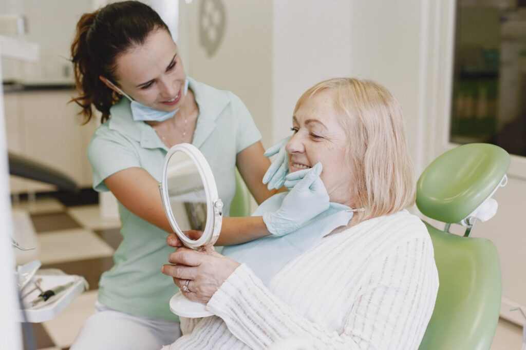 Mujer mayor que recibe tratamiento dental. La mujer del consultorio del dentista está siendo tratada y sabe cuáles son los 3 tipos de implantes dentales.