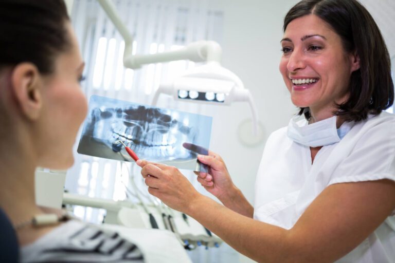 Dentista mostrando una radiografía a su paciente explicándole los beneficios de extraer las muelas del juicio