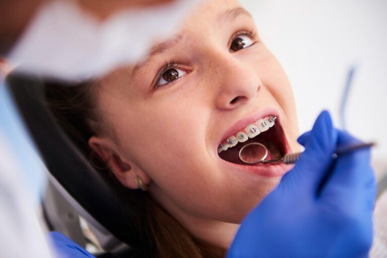 Niña con frenillos durante un examen dental de rutina conociendo los beneficios de corregir una sobremordida