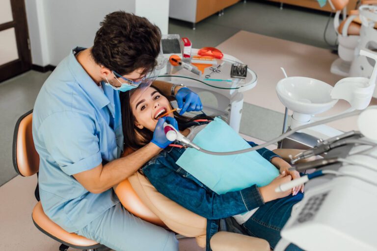 Young female patient with open mouth examining dental inspection at dentist office