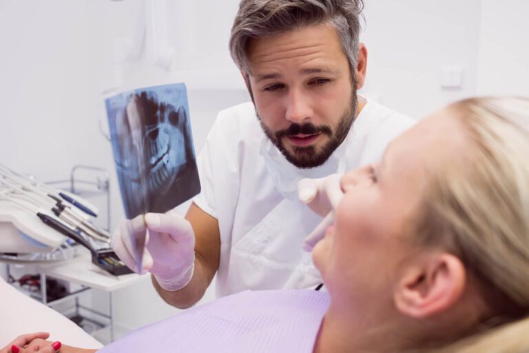 Dentist showing x-ray to the patient to explain which teeth are connected to the sinuses